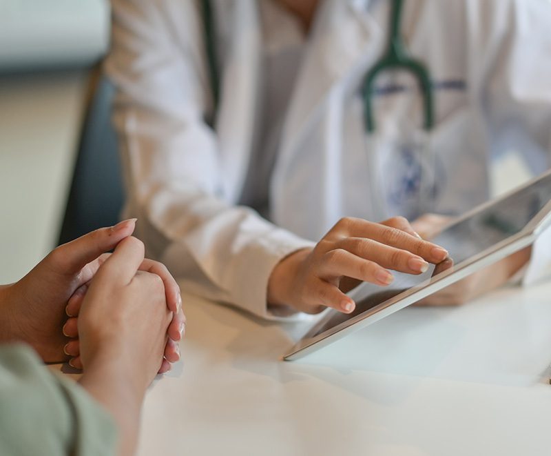 Doctor discussing treatment with patient while holding a tablet